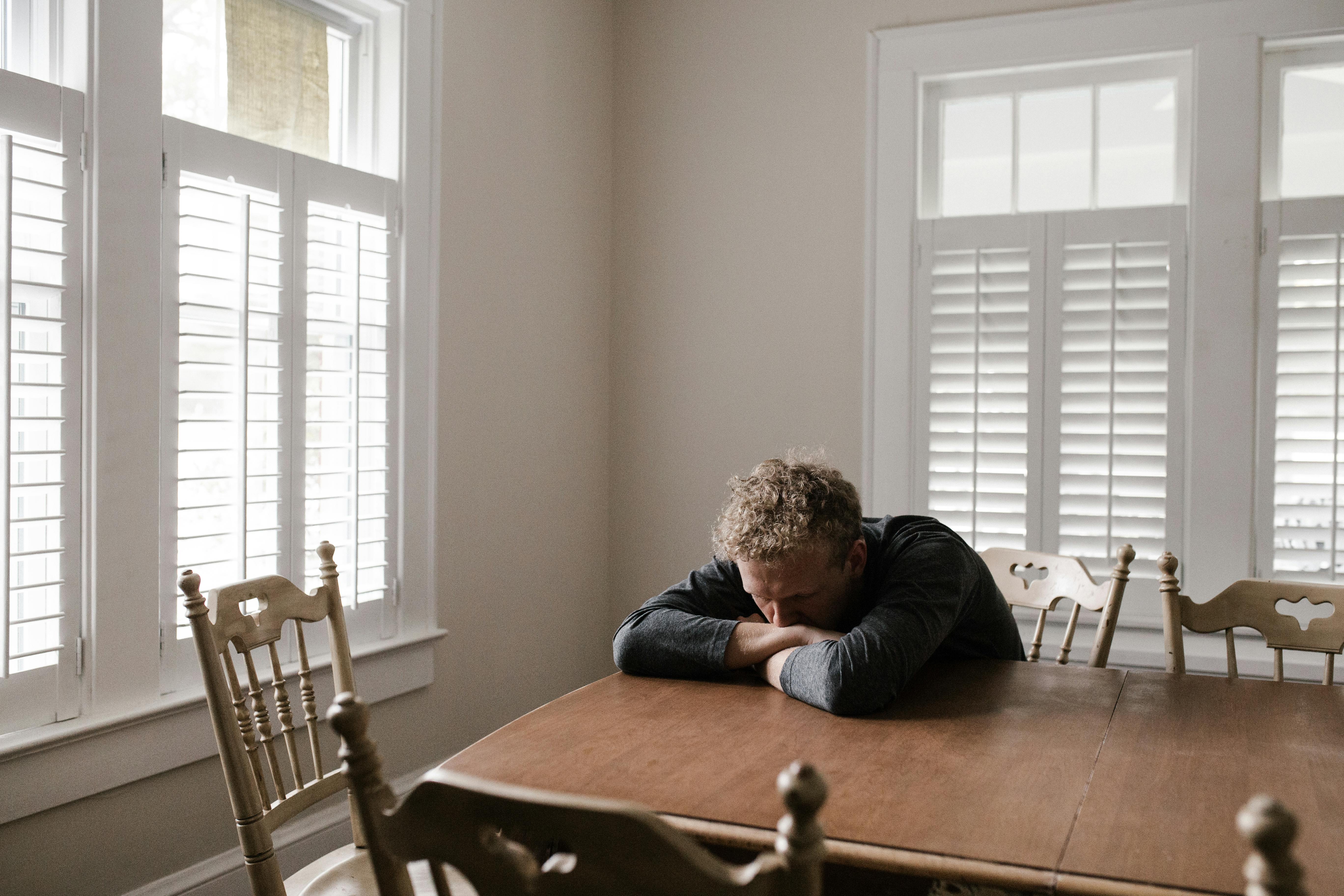 person appearing depressed sitting head in hands at a table